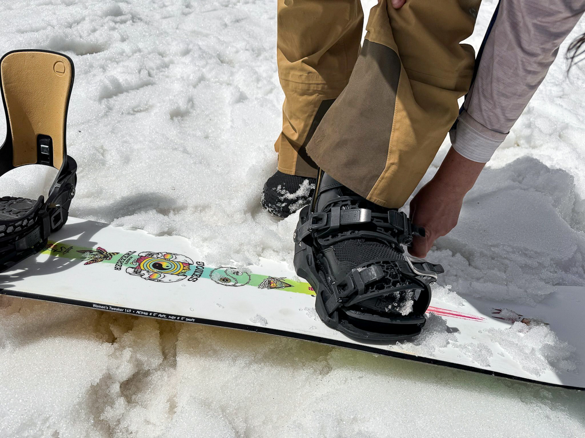 woman strapping into a snowboard binding