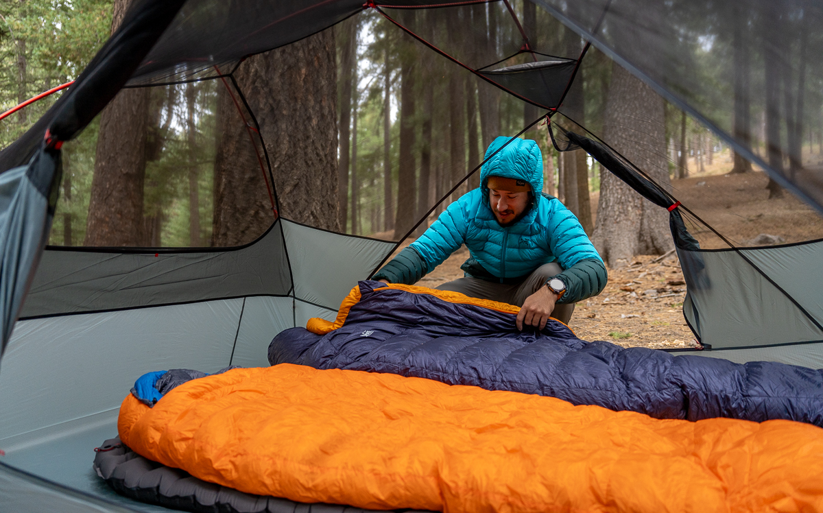 man setting up backpacking sleeping bags in a tent