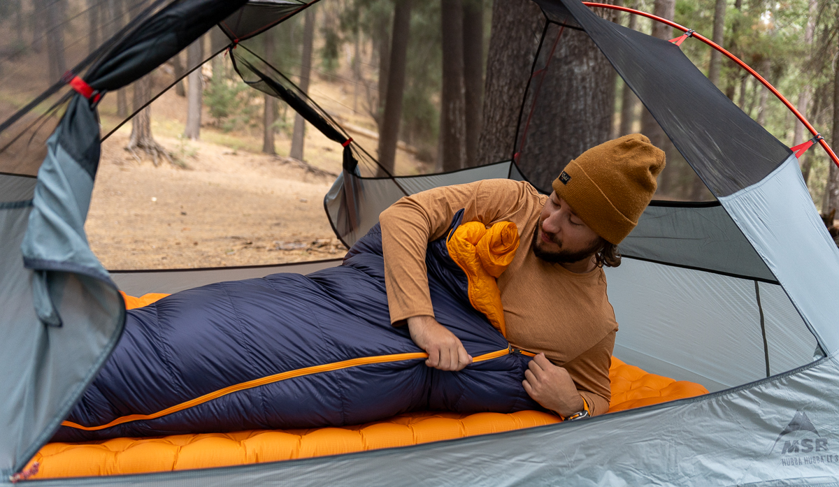 man zipping up sleeping bag