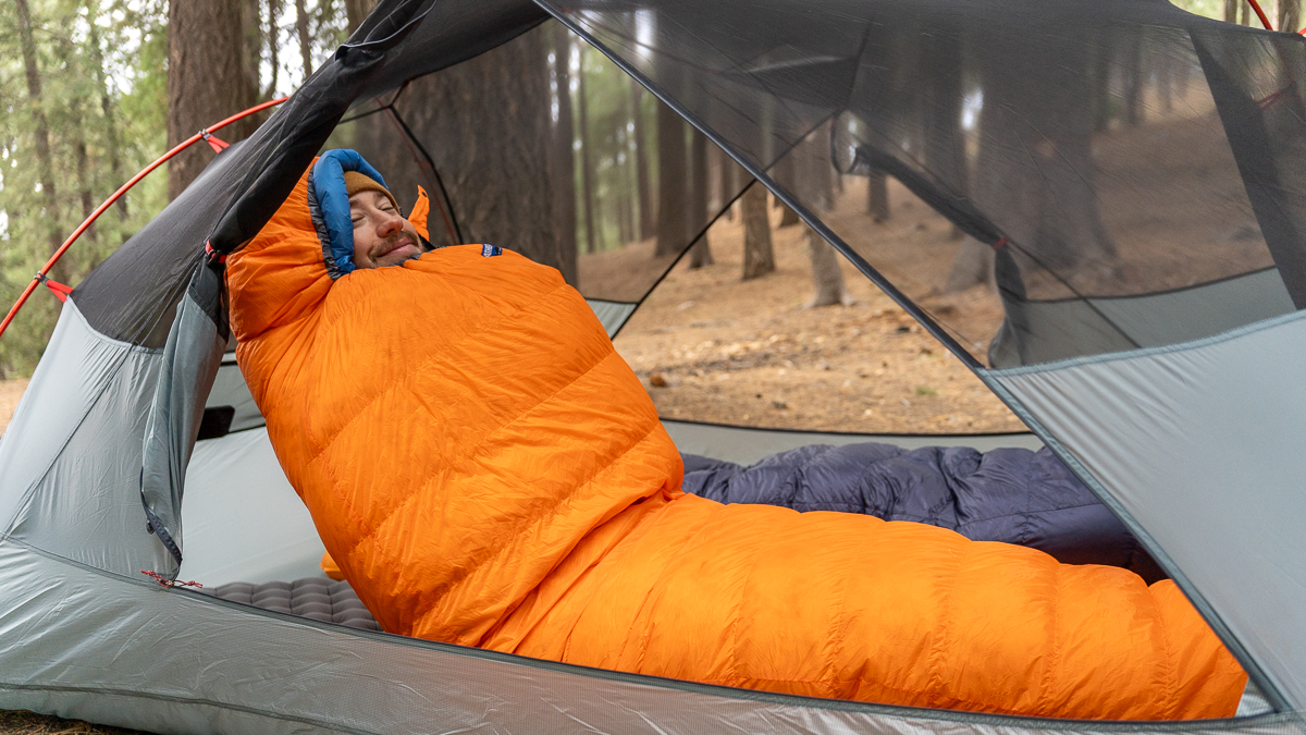 a man cozied up in a backpacking sleeping bag leaning back